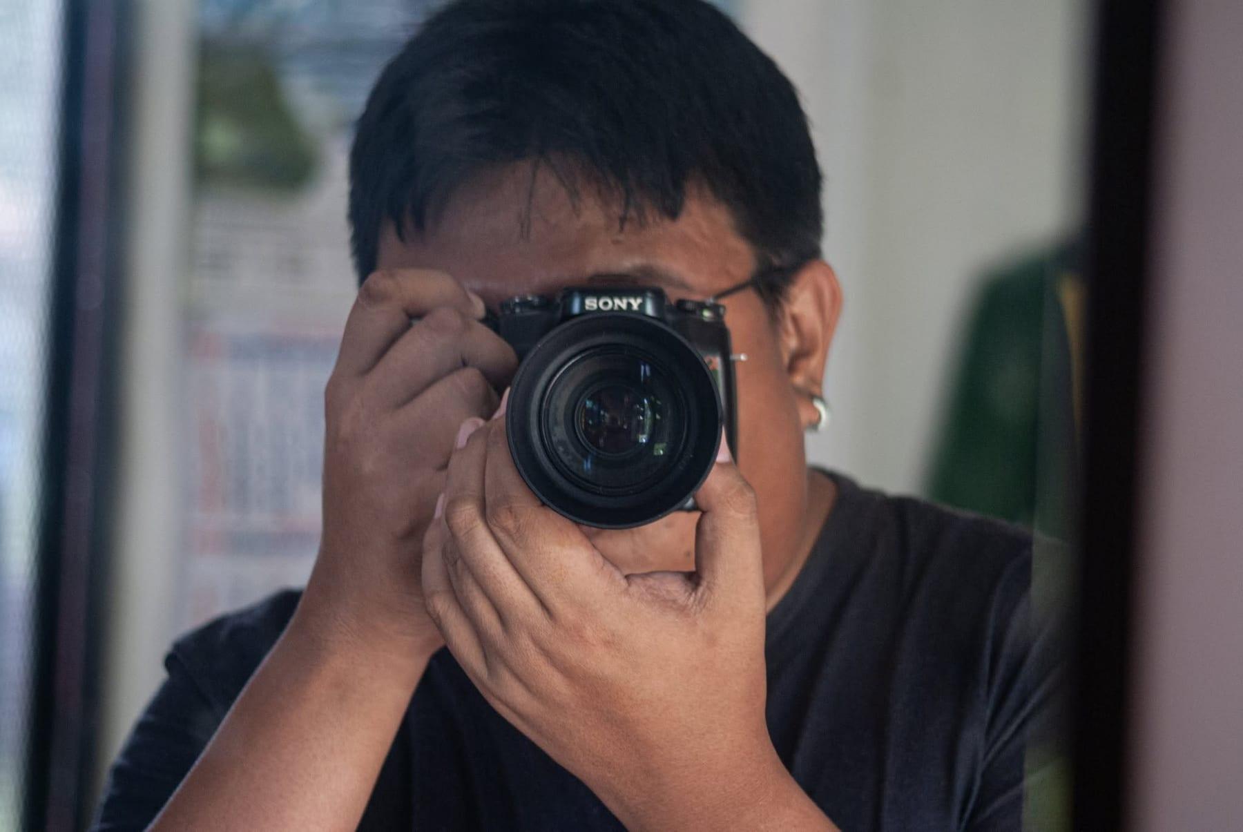 Mirror self-portrait of a photographer holding a black Sony camera up to his eye