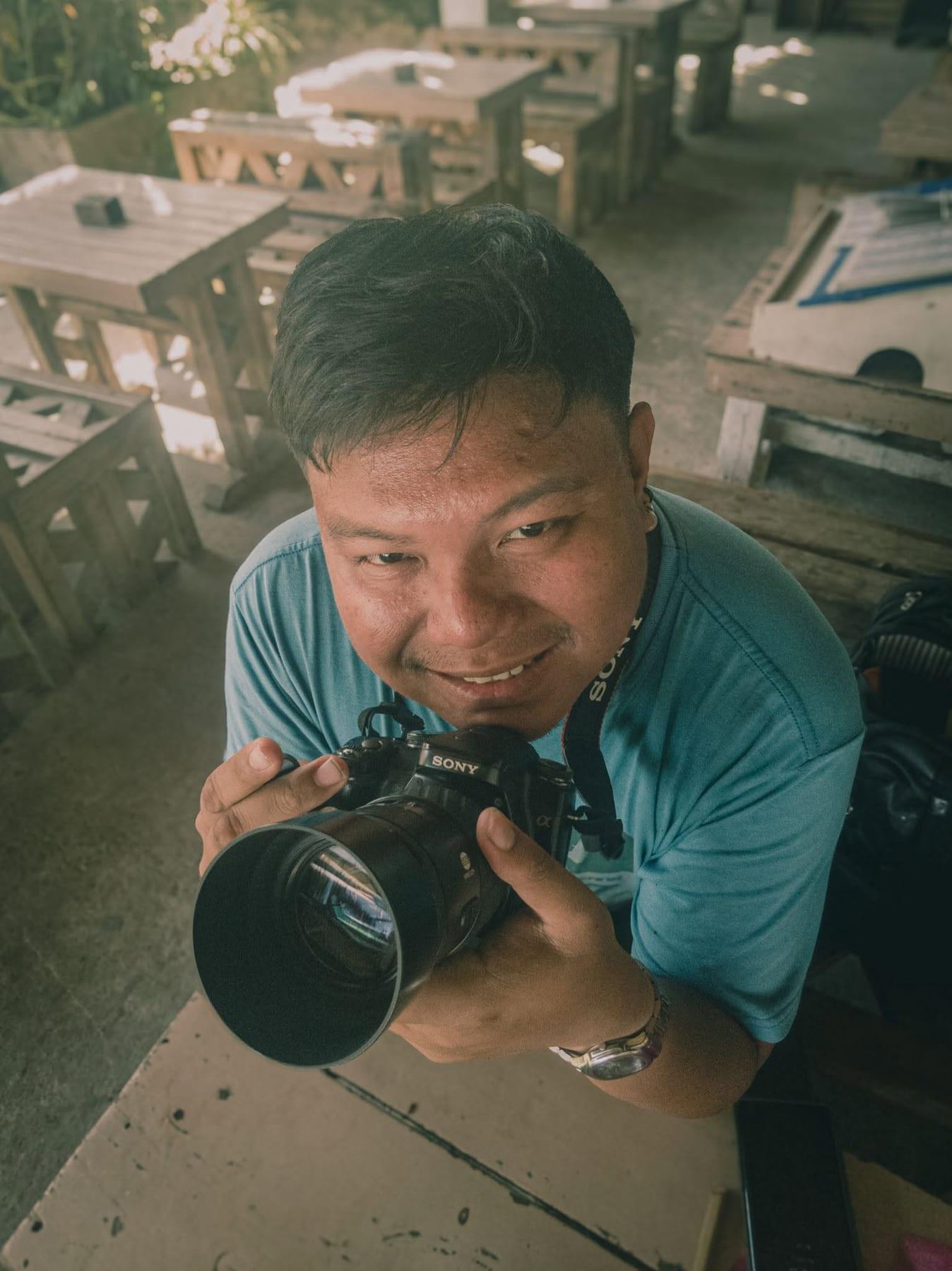Portrait of a smiling photographer holding a professional Sony camera outdoors